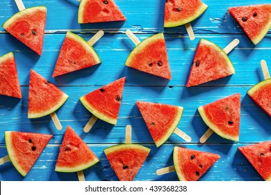 Watermelon slice popsicles on a blue rustic wood background - Shutterstock ID 439368238