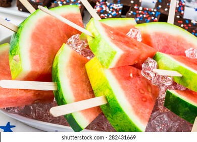Watermelon slice popsicles on serving plate with ice.