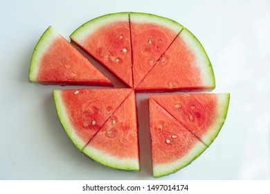 Watermelon sliced and cut into eight wedges on a white ceramic background