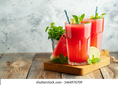 Watermelon slushie with lime and mint, summer refreshing drink in tall glasses on a light blue background. Sweet cold smoothie with copy space