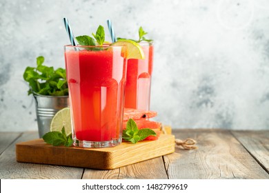 Watermelon slushie with lime and mint, summer refreshing drink in tall glasses on a light background. Sweet cold smoothie with copy space