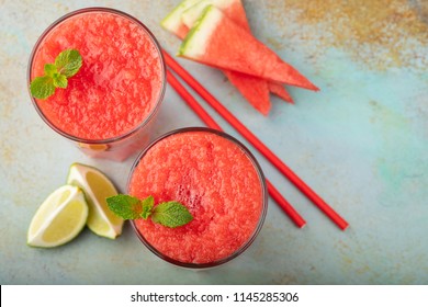 Watermelon slushie with lime, summer refreshing drink in tall glasses on a blue rusty background. Top view with copy space