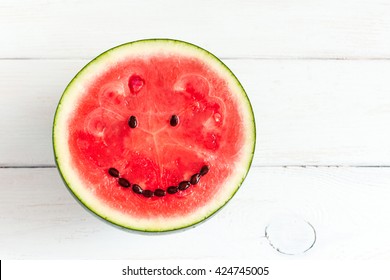 Watermelon with smile face. Funny watermelon on wooden white background. Top view, flat lay, copy space