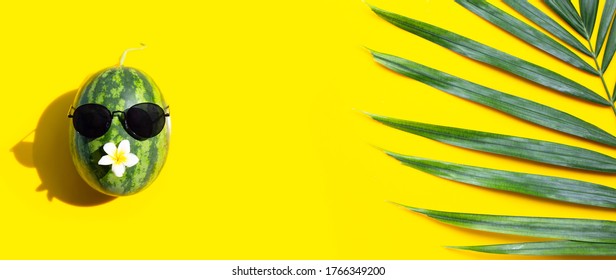 Watermelon with sunglasses and tropical palm leaves on yellow background. Enjoy summer holiday concept. - Powered by Shutterstock