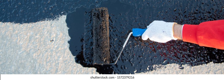 Waterproofing coating. Worker applies bitumen mastic on the foundation. Roofer cover the rooftop polymer modified bitumen waterproofing primer, with a roller brush. - Shutterstock ID 1572379216