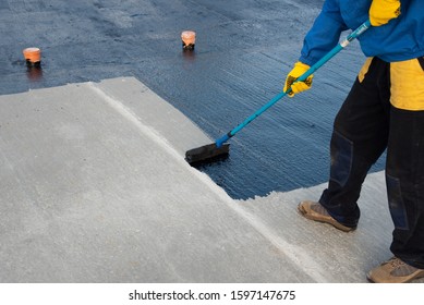 Waterproofing coating. Worker applies bitumen mastic on the foundation. Roofer cover the rooftop polymer modified bitumen waterproofing primer, with a roller brush.