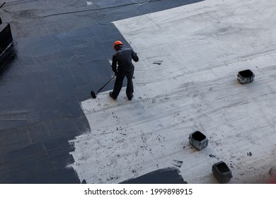 Waterproofing coating. A worker applies bitumen mastic to the foundation. Roofer cover the waterproofing primer on the roof, modified with polymer bitumen, with a roller brush. - Shutterstock ID 1999898915