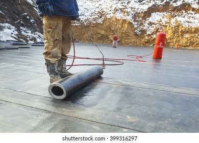 Waterproofing Roll Bituminous Material In The Trench. Construction Worker Manufacturer Uses A Gas Burner Propane Tank Fire.