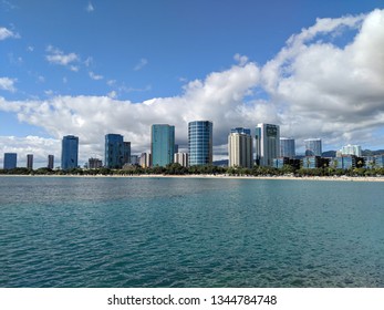 Waters and beach of Ala Moana Beach Park with office building and condos in the background during a beautiful day on the island of Oahu, Hawaii. 