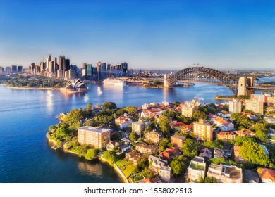 Waters of Sydney harbour between city CBD landmark builidings connected by the Sydney Harbour bridge to North Shore wealthy suburbs - elevated aerial view on a sunny day.