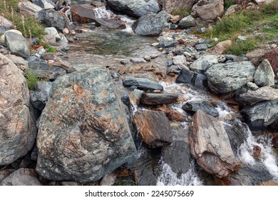 Waters of transparent alpine stream have been rushing down for centuries, washing granite boulders interspersed with various metals and minerals on their way, Cogne, Aosta valley, Italy - Powered by Shutterstock