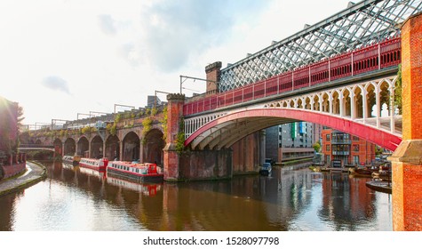 Waterway canal area with a narrowboat on the foreground modern bridge, Castlefield district - Manchester, UK