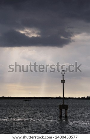 Waterway marker and uninhabited islands of Venetian lagoon with dark stormy sky in background. View from Burano island, Venice, Italy. Foto stock © 