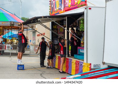 Wathena, Kansas / United States Of America - September 1st, 2019 : A Carnival Worker Lifts An Awning Over His Head While Setting Up A Game Booth At The Wathena Fall Festival.