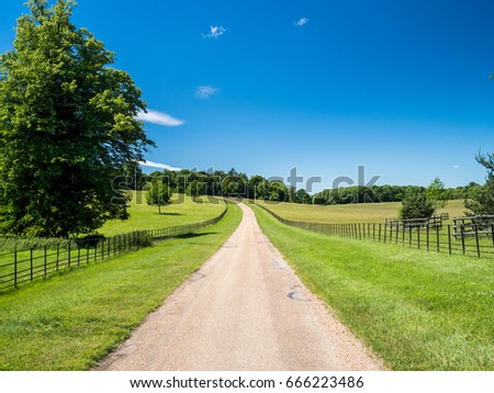 Watling Street, a Roman road in Great Britain, stretching to the horizon between green fields under a clear blue sky.