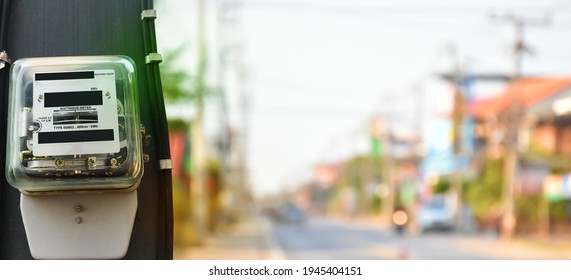 Watthour Metre Of Electricity Hanging On Pole Beside The Rural Road, Blurred Background.