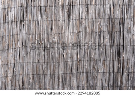 Wattle fence of dry horizontal twigs as the background. Traditional rustic fence. Abstract wooden backdrop.