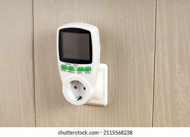 Wattmeter for measuring electricity costs in devices connected to outlet, saving, expense analysis, in socket on wall close-up - Shutterstock ID 2115568238