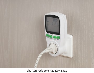 Wattmeter for measuring electricity costs with plug connected to the outlet, saving, expense analysis, in socket on wall close-up - Shutterstock ID 2112745592
