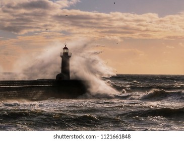 Wave against lighthouse of Porto, Portugal, in the sunset light