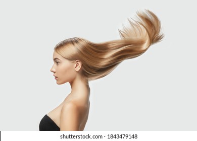 Wave. Beautiful model with long smooth, flying blonde hair on white studio background. Young caucasian model with well-kept skin and hair blowing on air. Concept of salon care, beauty, fashion.