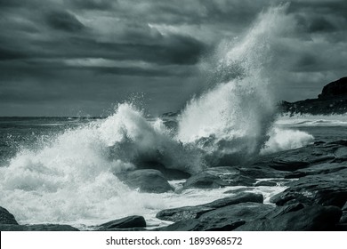 Wave breaking on rocky shore under cloudy sky - Powered by Shutterstock