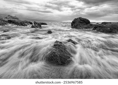 A Wave Is Breaking With Water Flowing Over Rocks In A Dramatic Black And White Seascape Image - Powered by Shutterstock