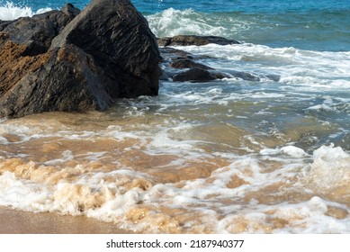 A wave breaks about a rock during a curtain on the sea. Farol da Barra beach, Salvador, Brazil.