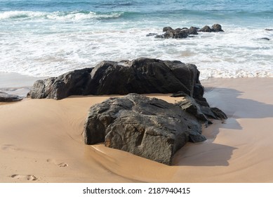 A wave breaks about a rock during a curtain on the sea. Farol da Barra beach, Salvador, Brazil.