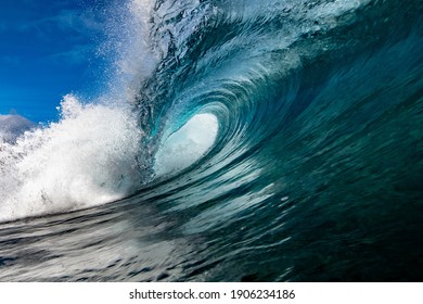 A wave breaks against the sea revealing a tube of water that fills with foam