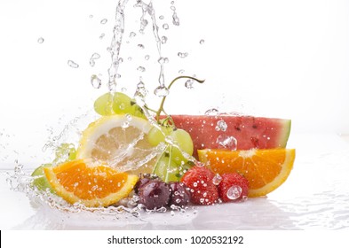 a wave of clear water falling on the varied and colorful fruits on a white background