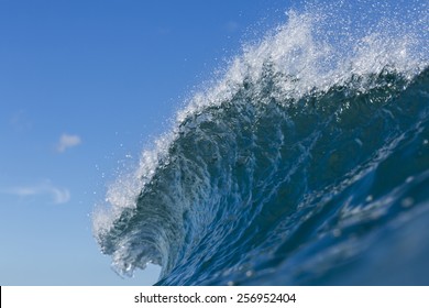 Wave Crest/ a wave peaks and crests against a blue sky 