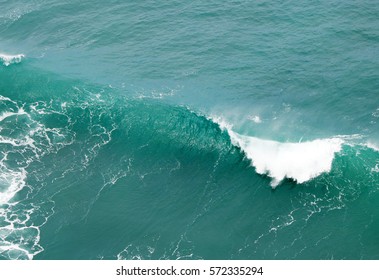 A wave falling into a water tube with a white cap and sun reflections - Shutterstock ID 572335294