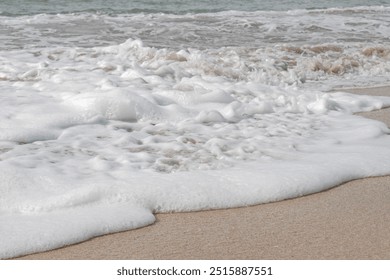 Wave foam texture photographed close up with soft yellow sand - Powered by Shutterstock