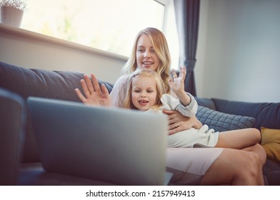 Wave Hello To Nana. Shot Of An Adorable Little Girl Using A Laptop With Her Mother On The Sofa At Home.