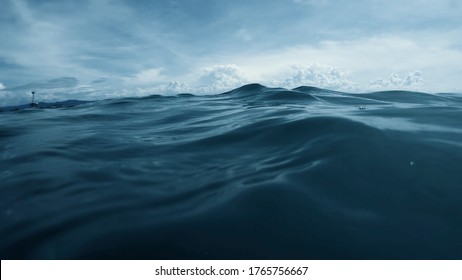 Wave on moving water surface close up in the middle of the screen.  Under Water Surface in the middle of the sea