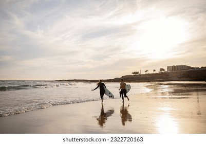 Wave Runners. Young Couple With Surfboards Going Into The Ocean, Millennial Man And Woman In Wetsuits Surfing On Sunset, Running To Hight Waves, Having Fun On The Beach Together, Copy Space - Powered by Shutterstock