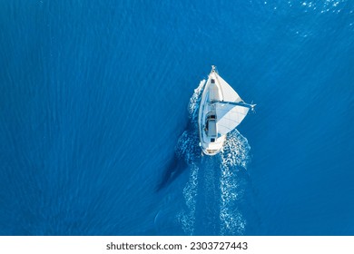 Wave and sail yacht on the sea as a background. 
Sea and waves from top view. Blue water background from top view. Top view from drone. Summertime vacation. Travel image