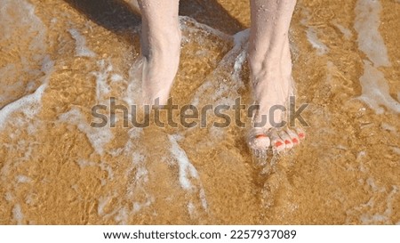 Wave washing over a women's feet at the beach