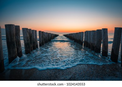 Wavebreakers at the beach in Zeeland during sunset