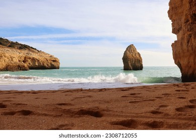 Waves in Atlantic Ocean with limestone cliffs on a sandy beach along the Seven Hanging Valleys Trail in southern Portugal on a sunny winter day.