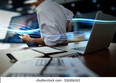 Waves of blue light and businessman using on smart phone and laptop computer as concept
