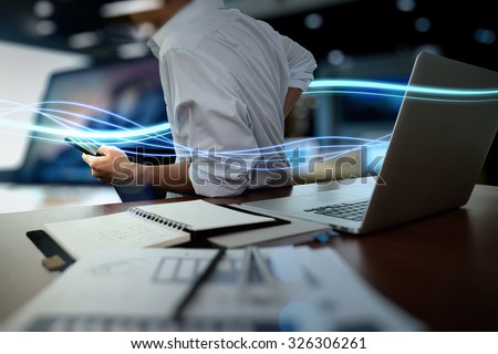Waves of blue light and businessman using on smart phone and laptop computer as concept