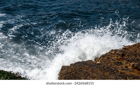 waves braking against rocks on a sunny day