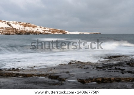 Waves braking on rocky shore on a cloudy winter day, Ekkerøya, Northern Norway