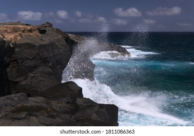 Waves are breaking against elevated rock shelf with salt evaporation ponds Salinas de Bufadero
