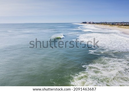 Waves breaking and being surfed by surfers in Long island, New York taken by drone.