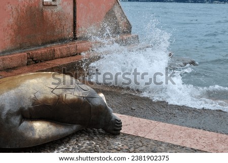 Waves Breaking over Stone Promenade with Bronze Sculpture 