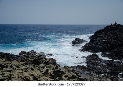 Waves Collide Against A Black Rock Formation.