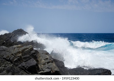 Waves Collide Against A Black Rock Formation.